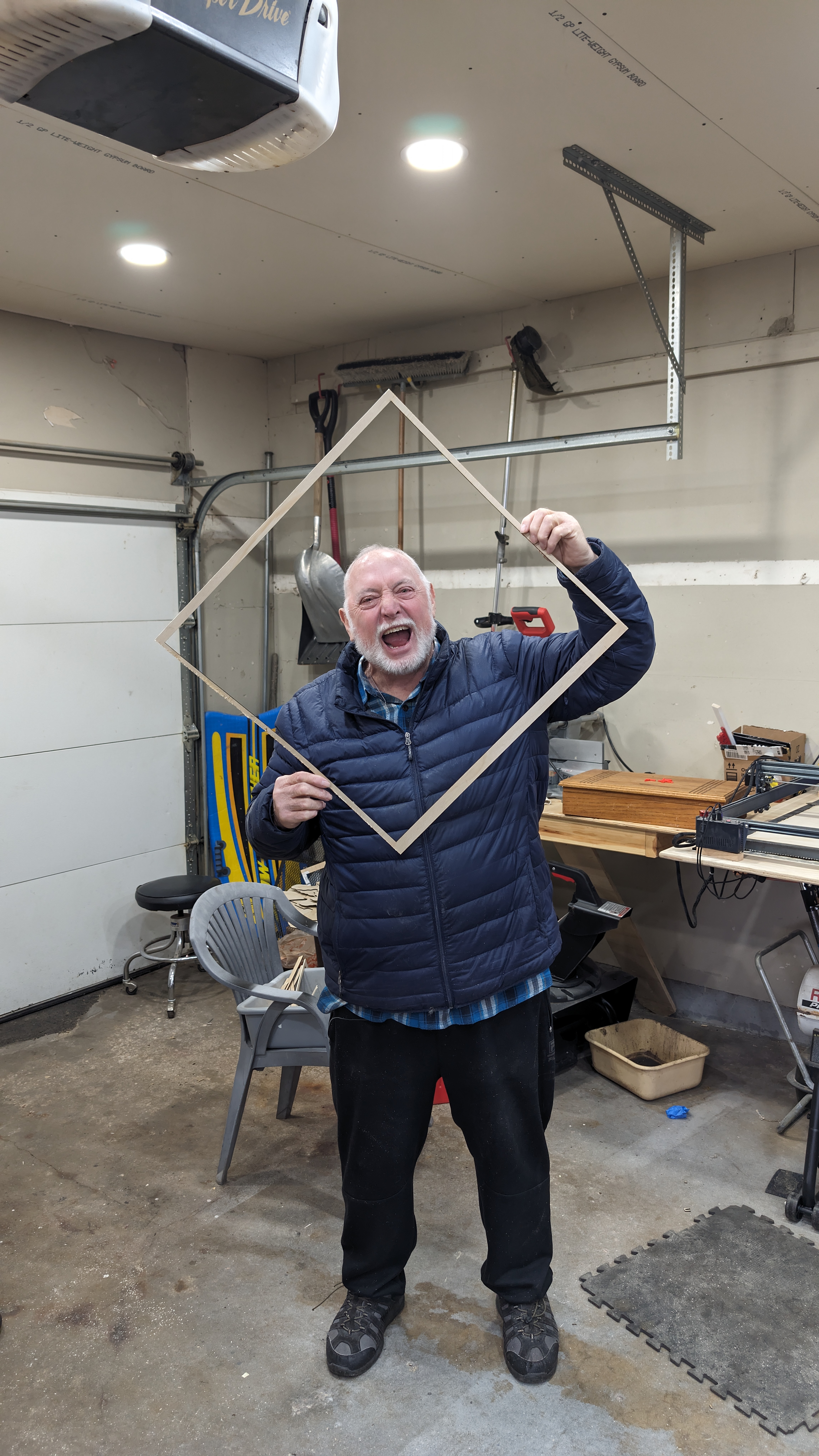 Chuck holding a diamond-shaped wood frame in the workshop